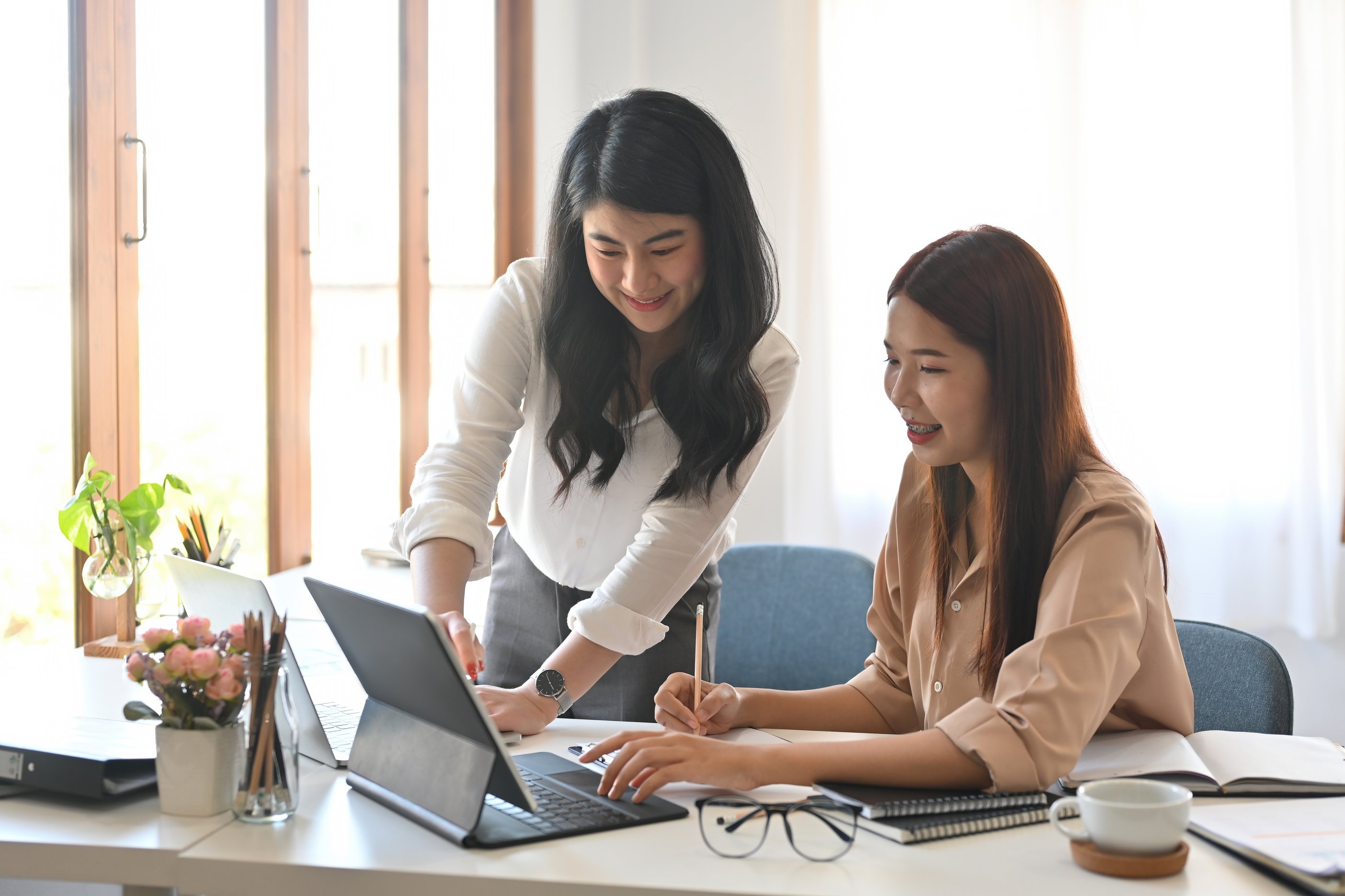 two beautiful smiley Asian employees working together in the